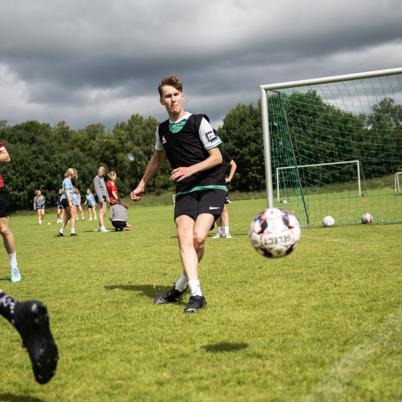 Elever fra Gudenaadalens Efterskole spiller fodbold på skolens udendørs fodboldbane.