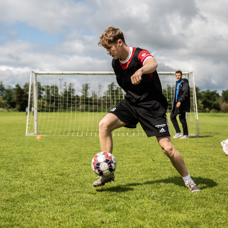Elev fra Gudenaadalens Efterskole spiller fodbold på skolens udendørs fodboldbane.