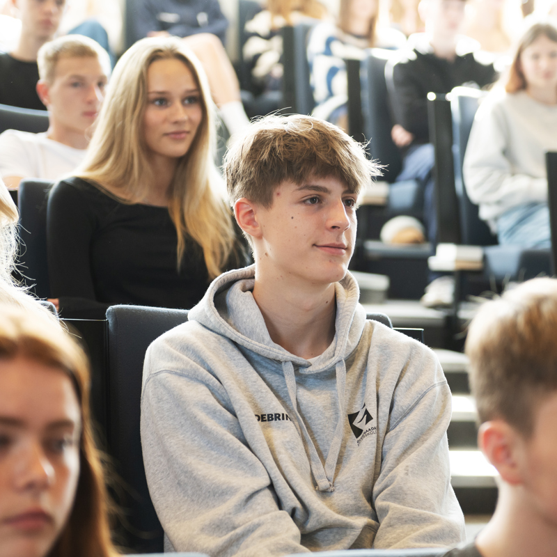 Efterskoleelever sidder i et auditorium og lytter på Gudenådalens efterskole. 