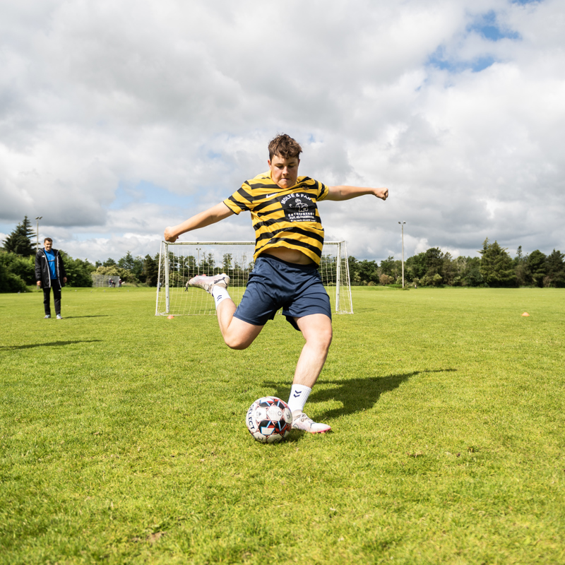Elev fra Gudenaadalens Efterskole spiller fodbold på skolens udendørs fodboldbane.
